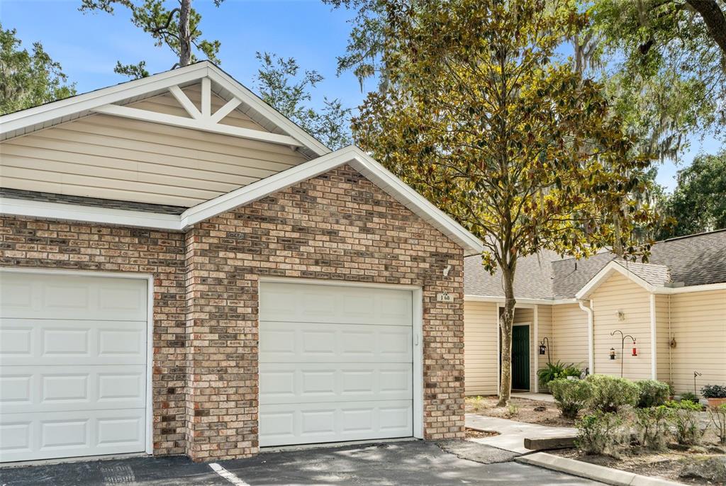 A brick and tan siding duplex features two garage doors and a shared front entrance — 4700 SW ARCHER ROAD UNIT 68, GAINESVILLE, FL