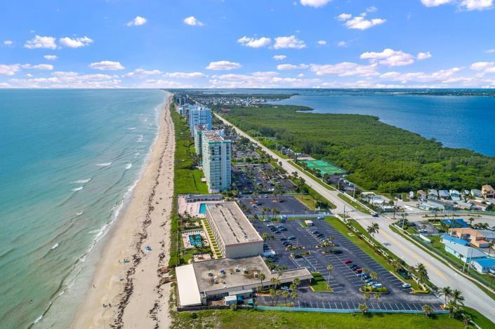 An aerial view of a coastal resort with high-rise buildings, parking lots, and a beach — 9800 S Ocean 107 Drive # 107, Jensen Beach FL 34957, JENSEN BEACH, FL