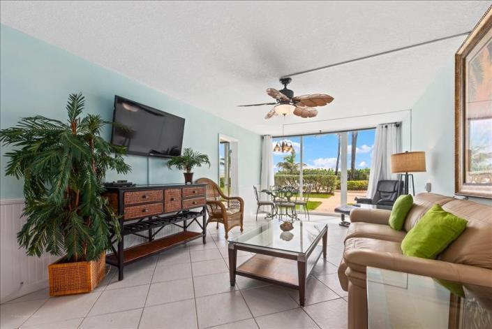 A living room features a tan leather sofa, glass coffee table, and a tropical ceiling fan — 9800 S Ocean 107 Drive # 107, Jensen Beach FL 34957, JENSEN BEACH, FL