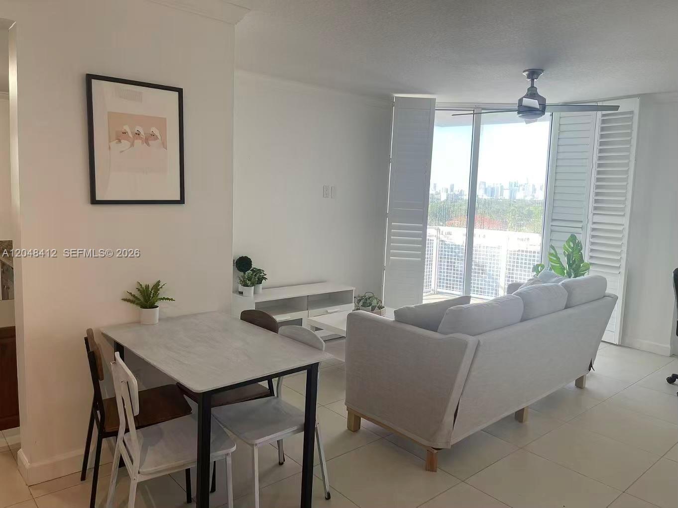 A bright living and dining area features a light-colored sofa, dining table, and balcony access — 2600 SW 27th Ave # 708, Miami FL 33133, MIAMI, FL