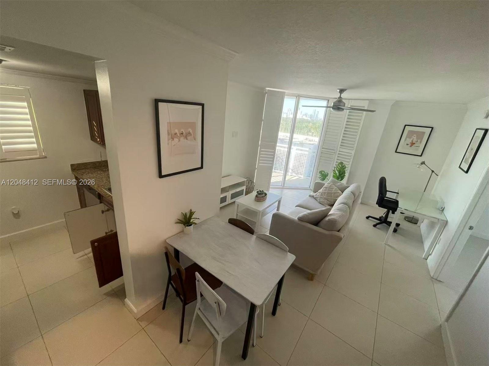An open-concept living and dining area features white tile floors and a balcony view — 2600 SW 27th Ave # 708, Miami FL 33133, MIAMI, FL