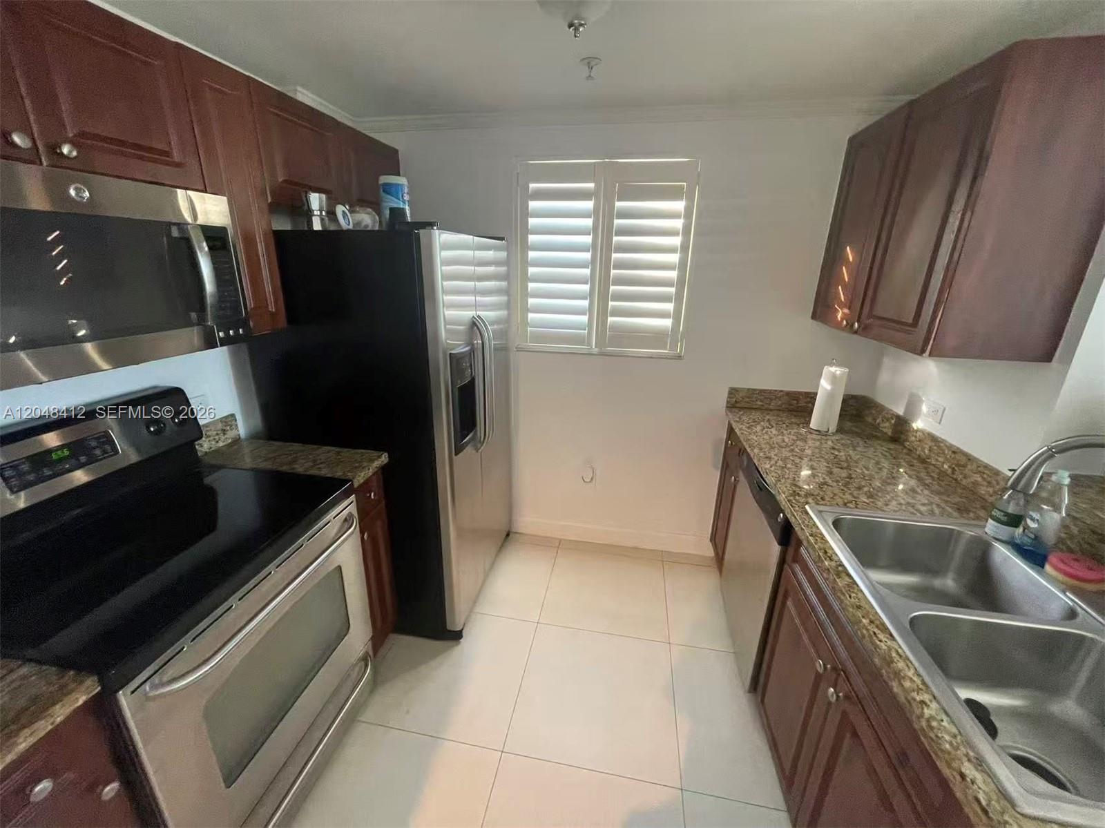 A kitchen features dark wood cabinets, granite countertops, stainless steel appliances, and white tile flooring — 2600 SW 27th Ave # 708, Miami FL 33133, MIAMI, FL