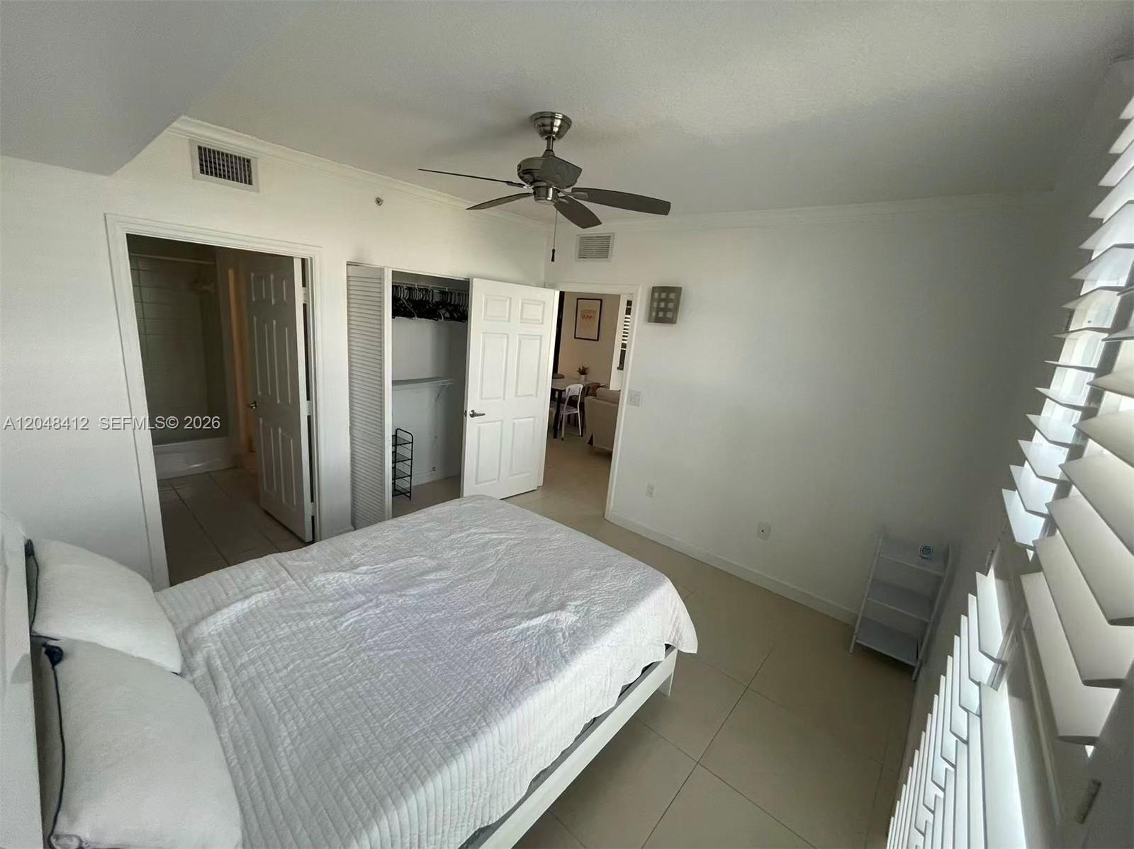 A bedroom with tile flooring, a ceiling fan, a closet, and an attached bathroom — 2600 SW 27th Ave # 708, Miami FL 33133, MIAMI, FL
