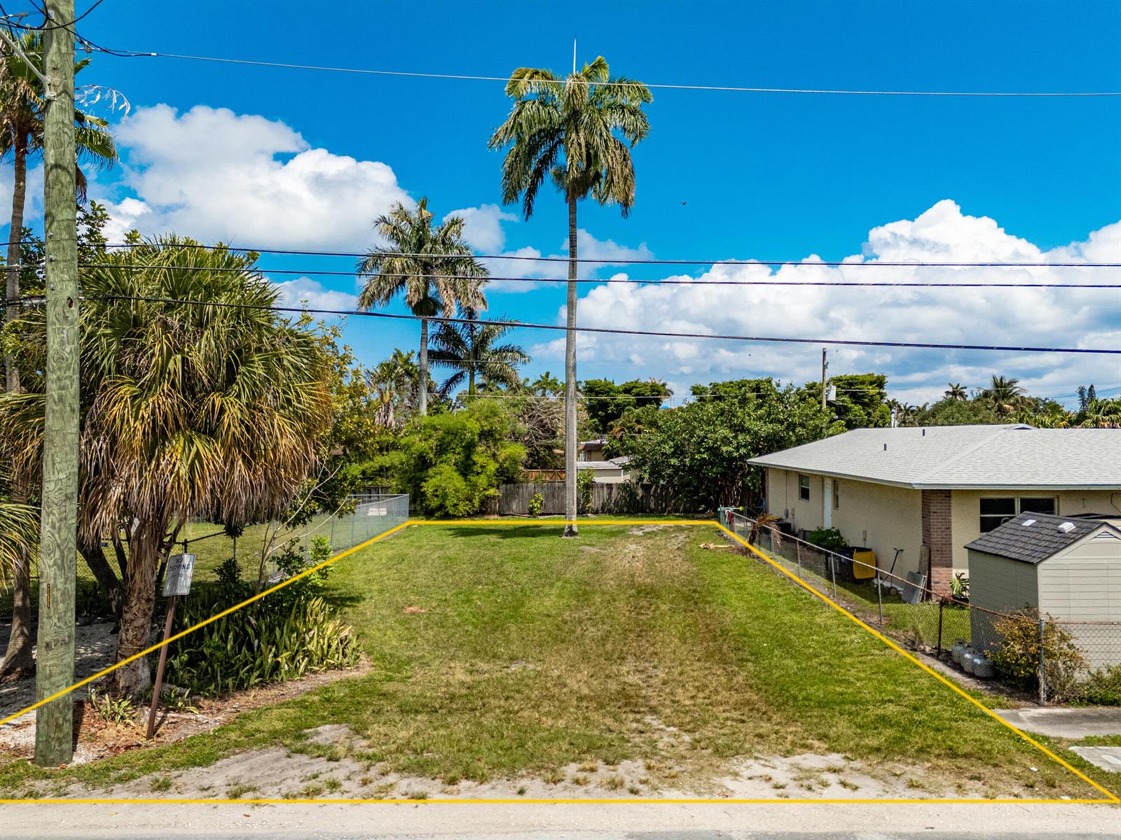 A vacant, rectangular grassy lot is outlined in yellow between a house and trees — 0 NE 1st Avenue, Dania Beach FL 33004, DANIA BEACH, FL