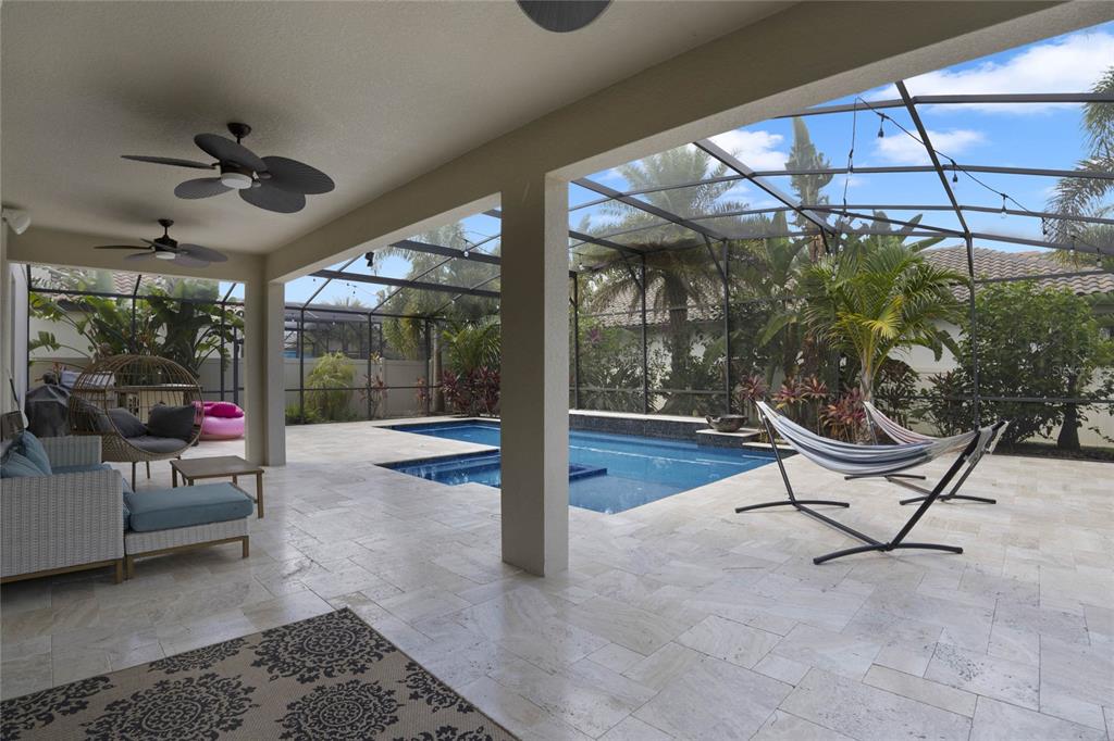 A covered patio features travertine flooring, ceiling fans, and a screened-in pool area — 8414 VIVARO ISLE WAY, WINDERMERE, FL