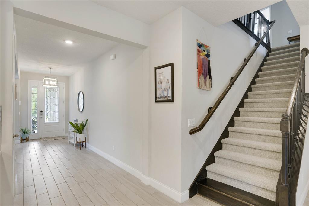 A bright entryway features light tile flooring, a staircase with carpeted steps, and a front door — 8414 VIVARO ISLE WAY, WINDERMERE, FL