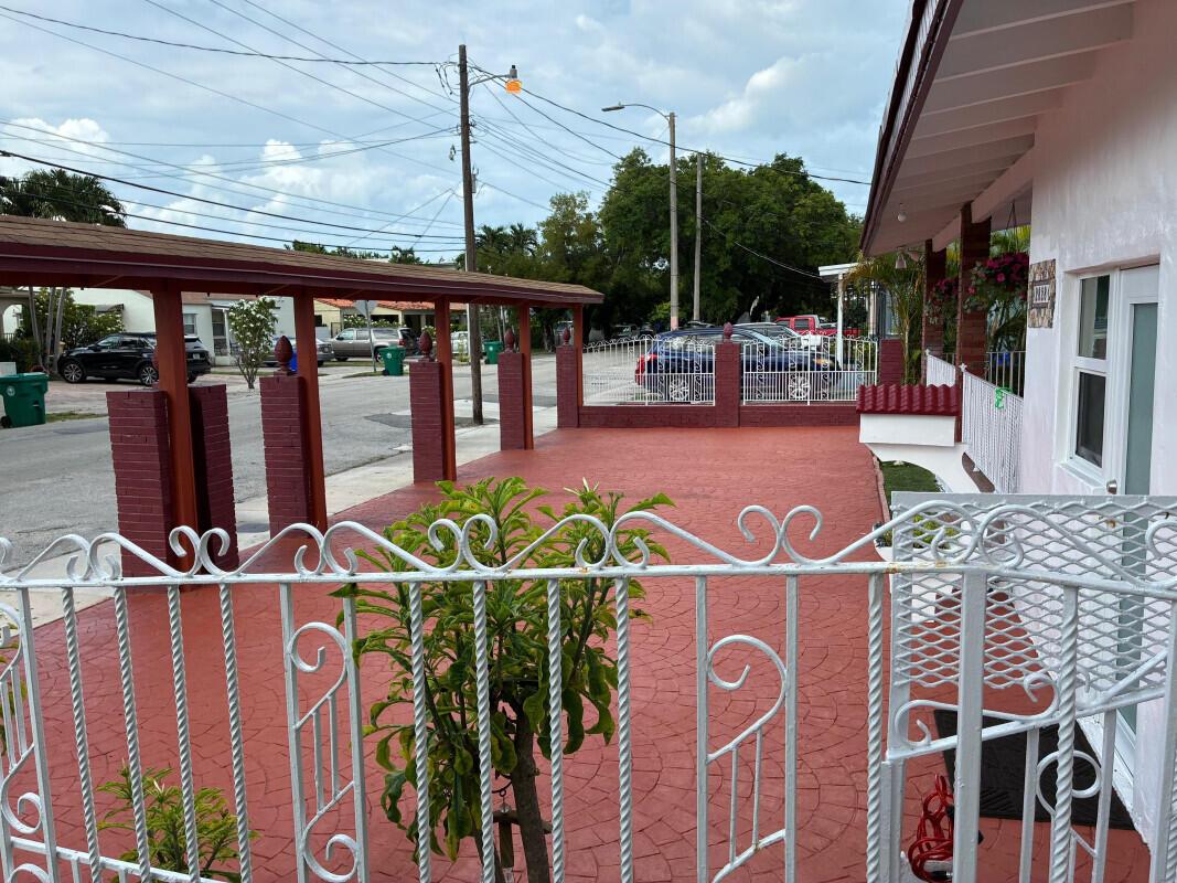 A red stamped concrete driveway and carport area are enclosed by a white metal fence — 2828 SW 2nd Street, Miami FL 33135, MIAMI, FL