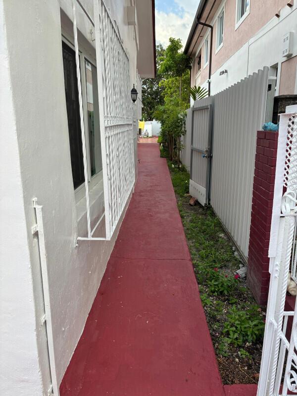 A narrow red concrete walkway runs between a white building and a metal fence — 2828 SW 2nd Street, Miami FL 33135, MIAMI, FL