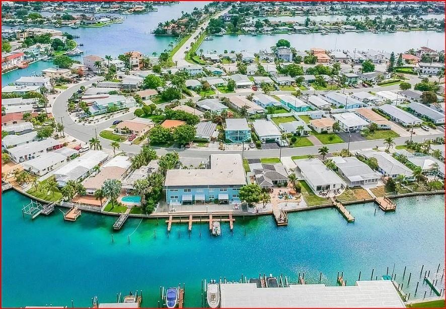 An aerial view of a waterfront residential neighborhood featuring a multi-unit building with boat docks — 11440 1ST STREET E UNIT 6, TREASURE ISLAND, FL