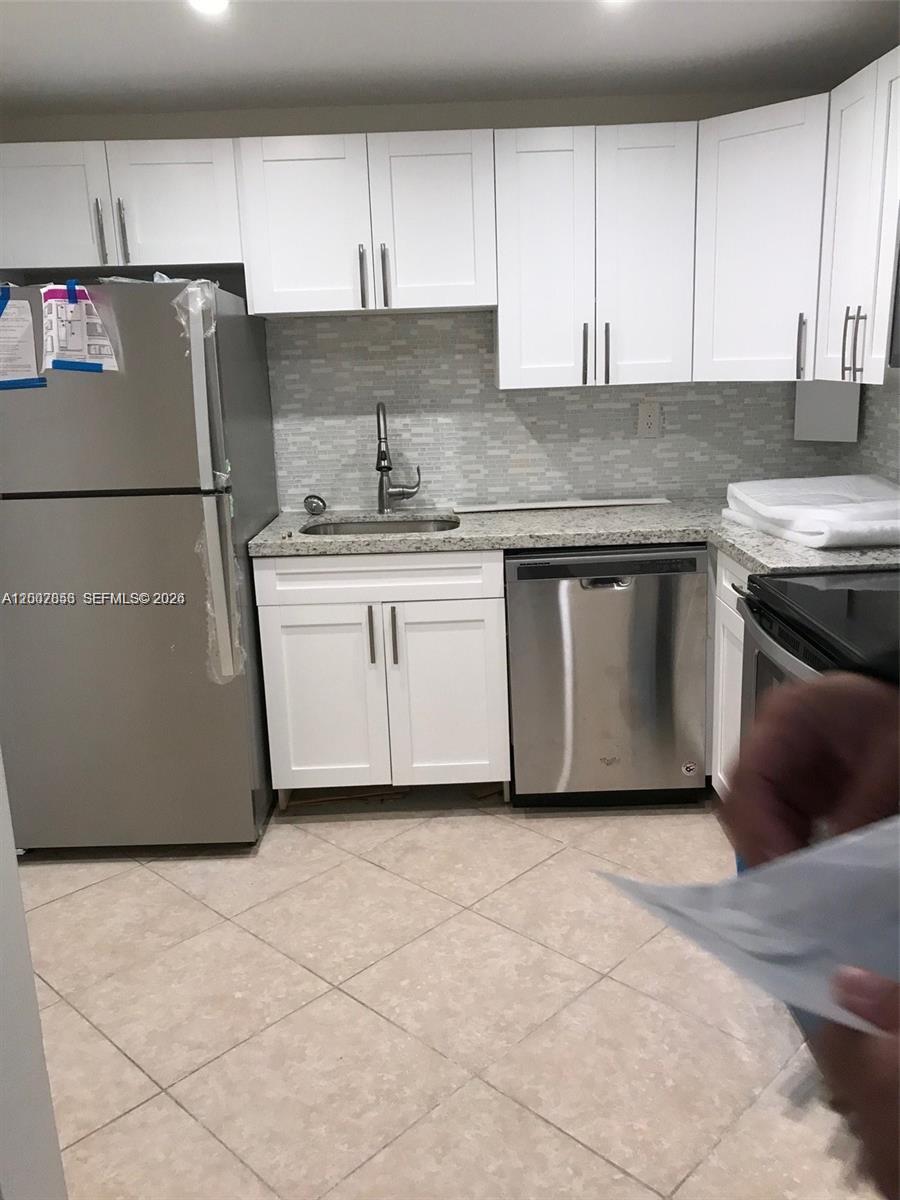 A kitchen features white cabinets, stainless steel appliances, granite countertops, and a tiled backsplash — 200 178th Dr # 505, Sunny Isles Beach FL 33160, SUNNY ISLES BEACH, FL