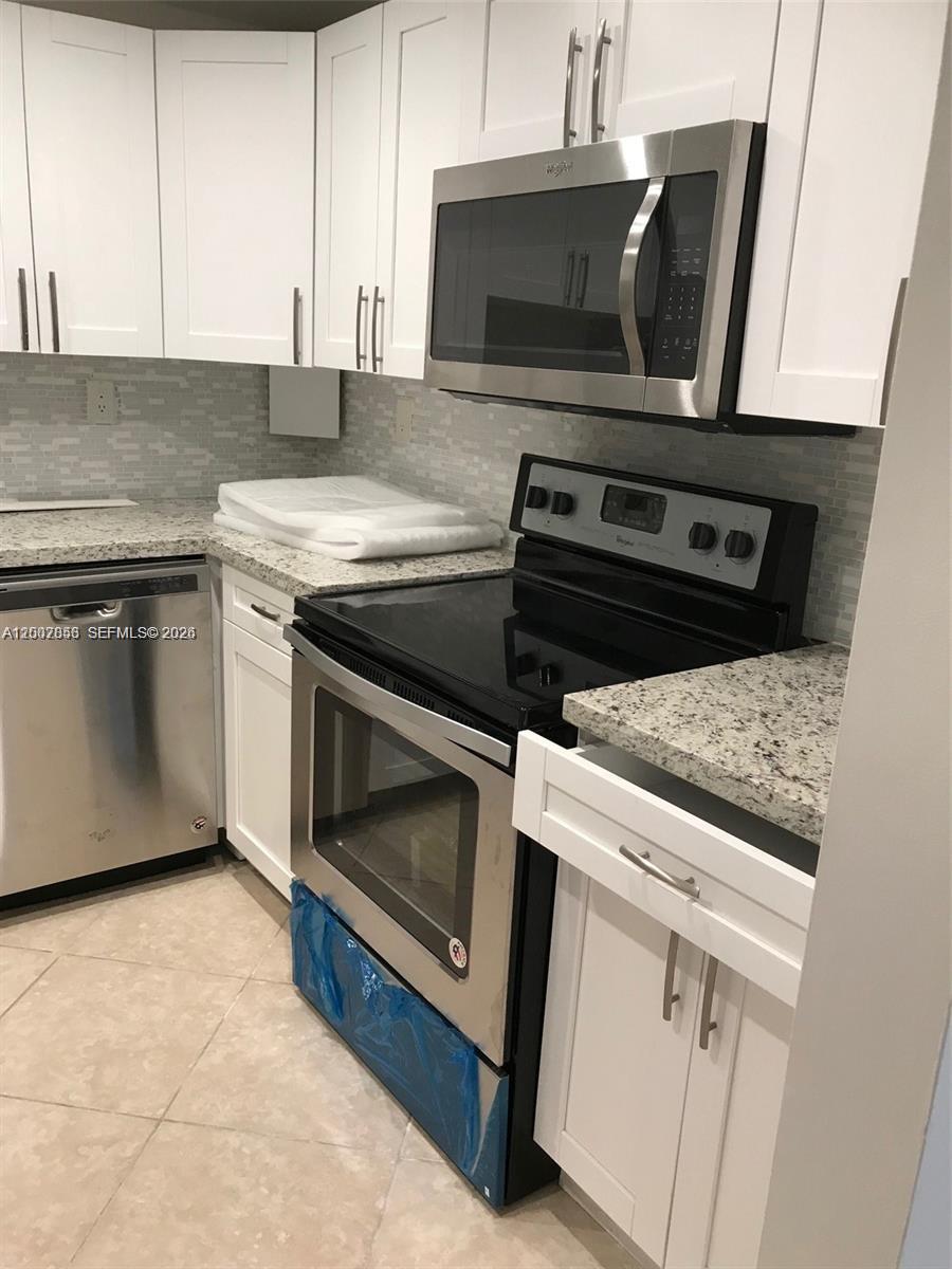 A kitchen features white cabinets, granite countertops, and stainless steel appliances — 200 178th Dr # 505, Sunny Isles Beach FL 33160, SUNNY ISLES BEACH, FL