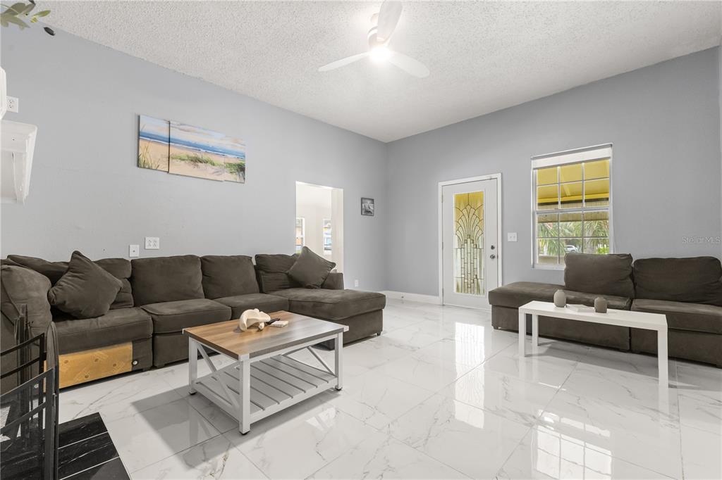 A living room features gray sectional sofas, a coffee table, and white marble-look tile flooring — 306 MARSHALL STREET, CLEARWATER, FL