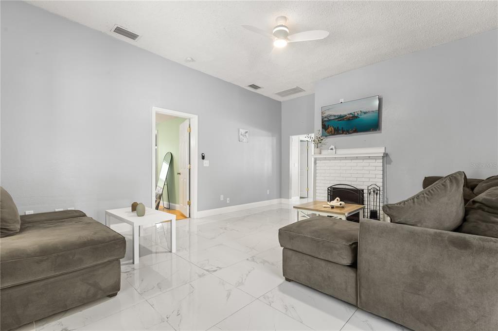 A living room with gray sofas, a white fireplace, and white tile flooring — 306 MARSHALL STREET, CLEARWATER, FL