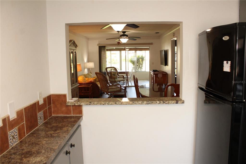 A kitchen pass-through window overlooks a dining area and living room with a ceiling fan — 5062 LIVE OAK CIRCLE UNIT 5026, BRADENTON, FL