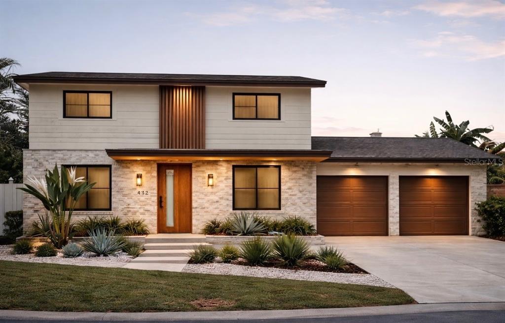 A two-story house with white siding, stone veneer, a wooden front door, and a garage — 7886 9TH AVENUE S, ST PETERSBURG, FL