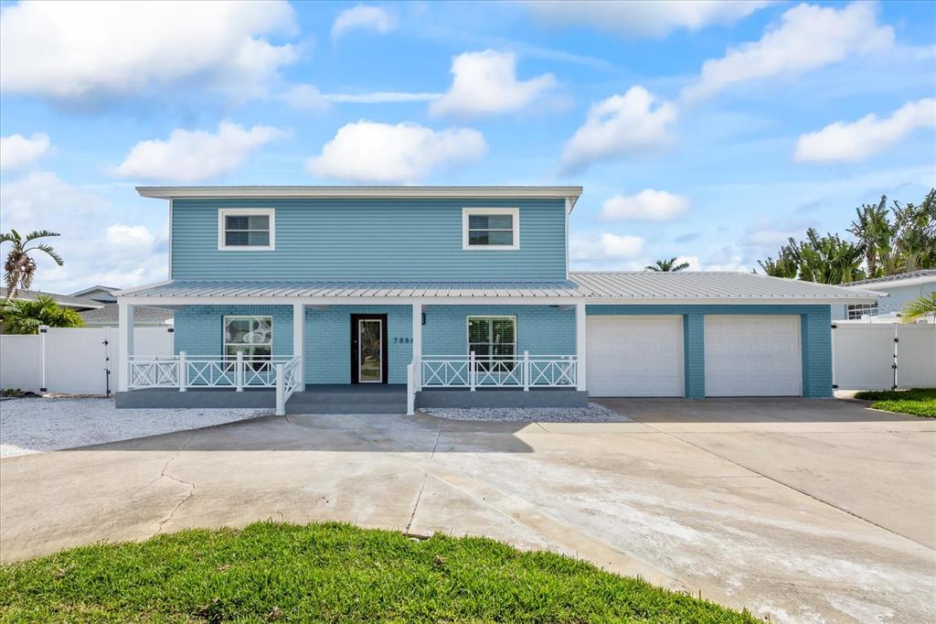 A two-story light blue house with a white porch, metal roof, and two-car garage — 7886 9TH AVENUE S, ST PETERSBURG, FL