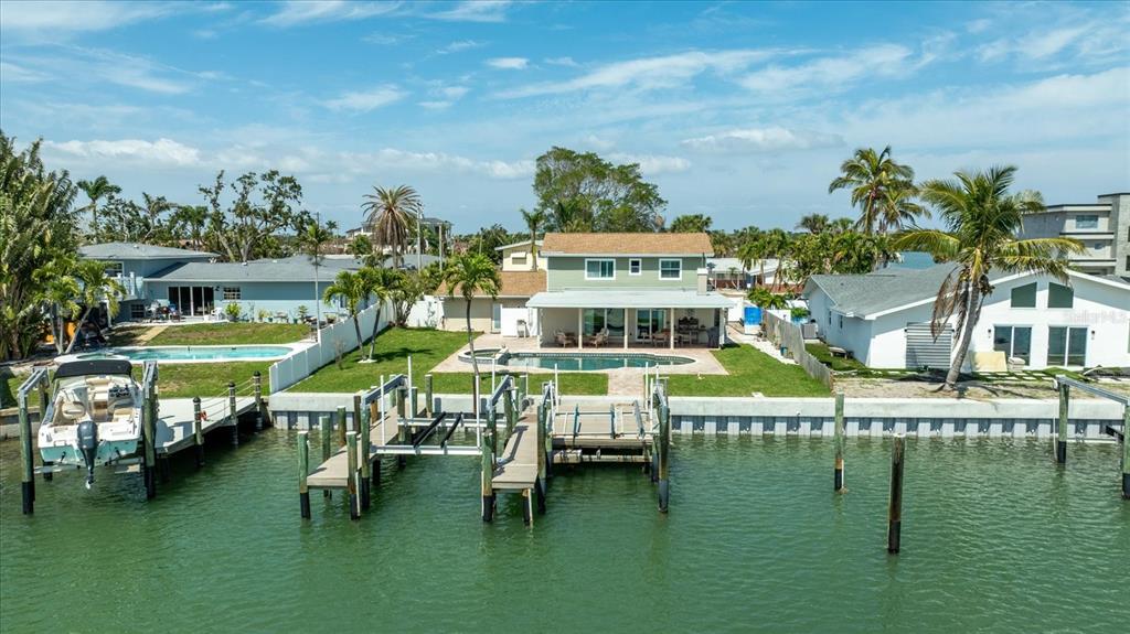 An aerial view of a waterfront house with a pool, boat dock, and palm trees — 7886 9TH AVENUE S, ST PETERSBURG, FL