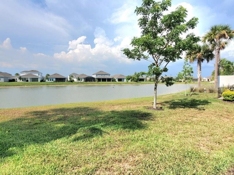 A grassy yard overlooks a pond with residential houses in the background — 16087 IVY RIDGE COURT, PORT CHARLOTTE, FL