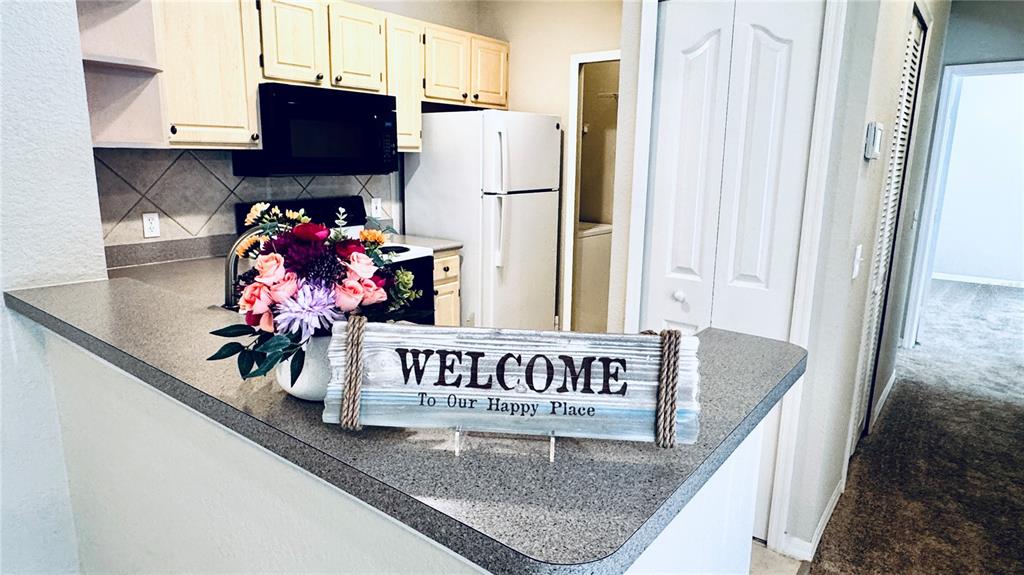 A kitchen features light wood cabinets, a white refrigerator, and a welcome sign on the counter — 1375 LAKE SHADOW CIRCLE UNIT 11203, MAITLAND, FL