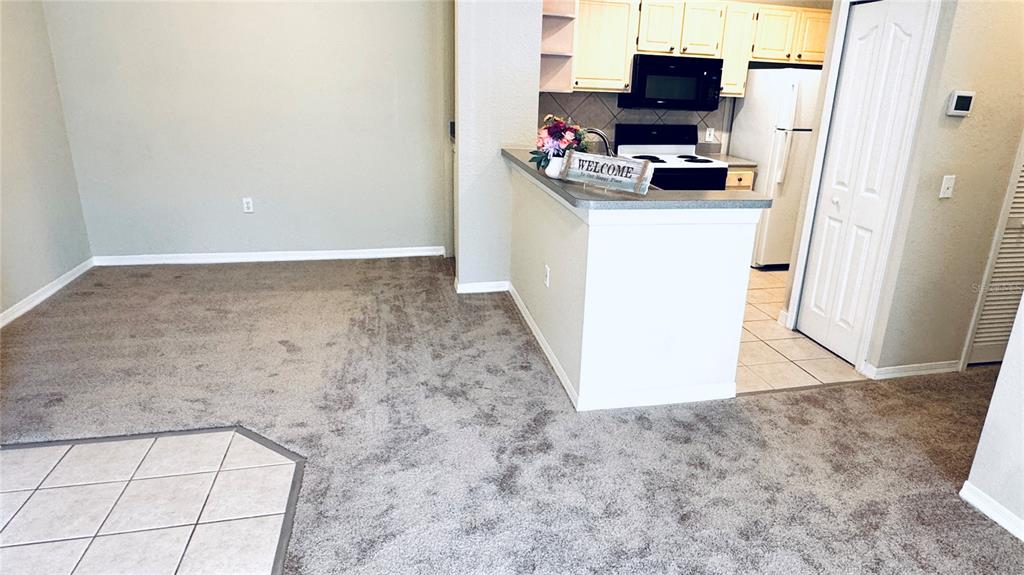 A carpeted dining area sits adjacent to a kitchen with light cabinets and white appliances — 1375 LAKE SHADOW CIRCLE UNIT 11203, MAITLAND, FL