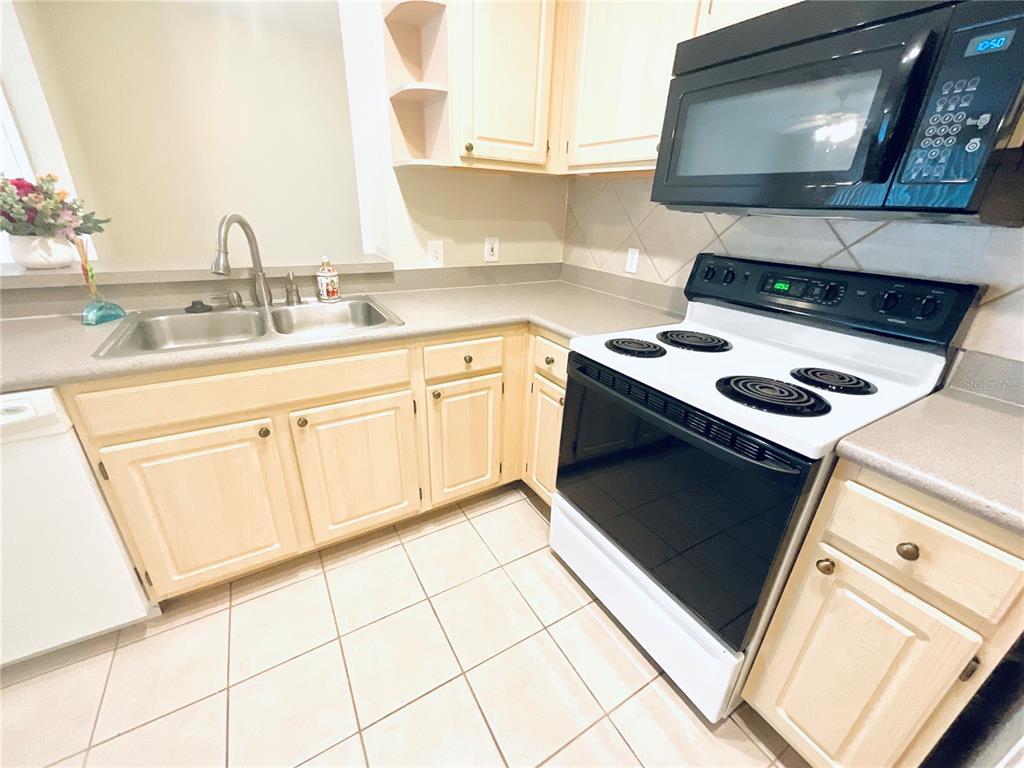 A kitchen features light wood cabinets, a double sink, and a white electric range — 1375 LAKE SHADOW CIRCLE UNIT 11203, MAITLAND, FL