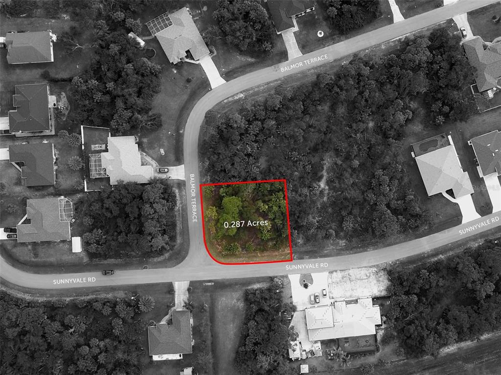 An aerial view shows a vacant, wooded corner lot outlined in red at a street intersection — SUNNYVALE ROAD, NORTH PORT, FL