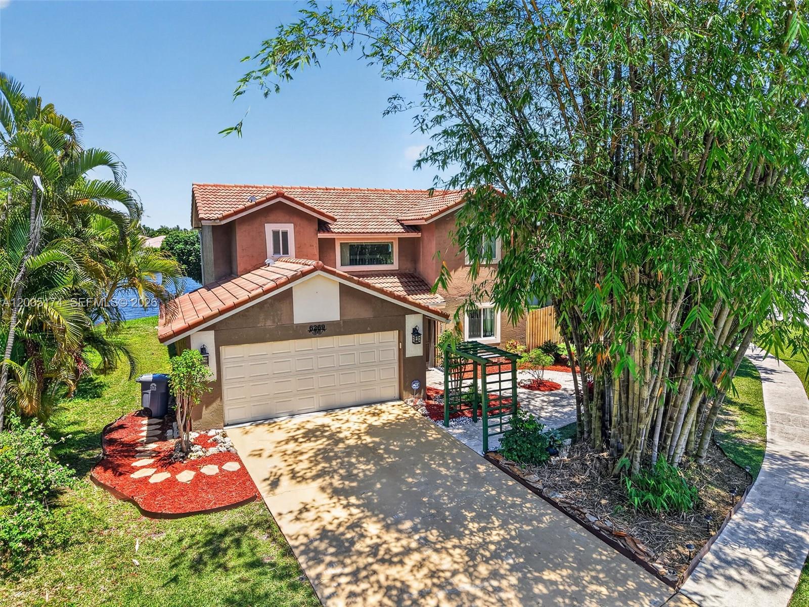 An aerial view of a two-story house with a tile roof, garage, and bamboo trees — 6269 Country Fair Circle, Boynton Beach FL 33437, BOYNTON BEACH, FL