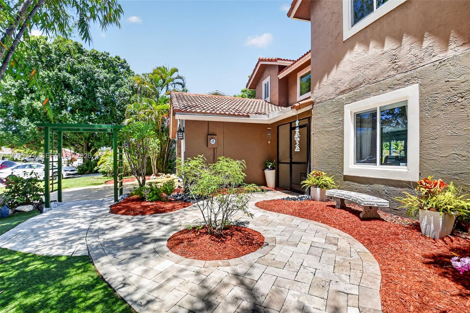 A paved walkway leads to the entrance of a two-story house with brown stucco walls — 6269 Country Fair Circle, Boynton Beach FL 33437, BOYNTON BEACH, FL