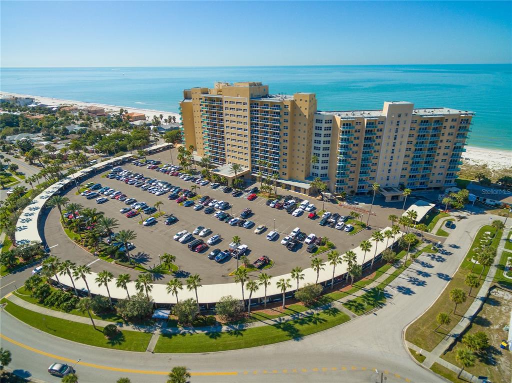 An aerial view shows a large beachfront apartment complex with a surrounding parking lot — 880 MANDALAY AVENUE UNIT S804, CLEARWATER BEACH, FL