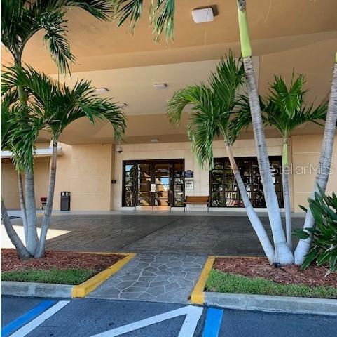 A covered entrance with palm trees leads to a building with glass double doors — 880 MANDALAY AVENUE UNIT S804, CLEARWATER BEACH, FL