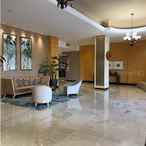 A lobby features a sofa, armchairs, a patterned rug, and wood paneling on a marble floor — 880 MANDALAY AVENUE UNIT S804, CLEARWATER BEACH, FL