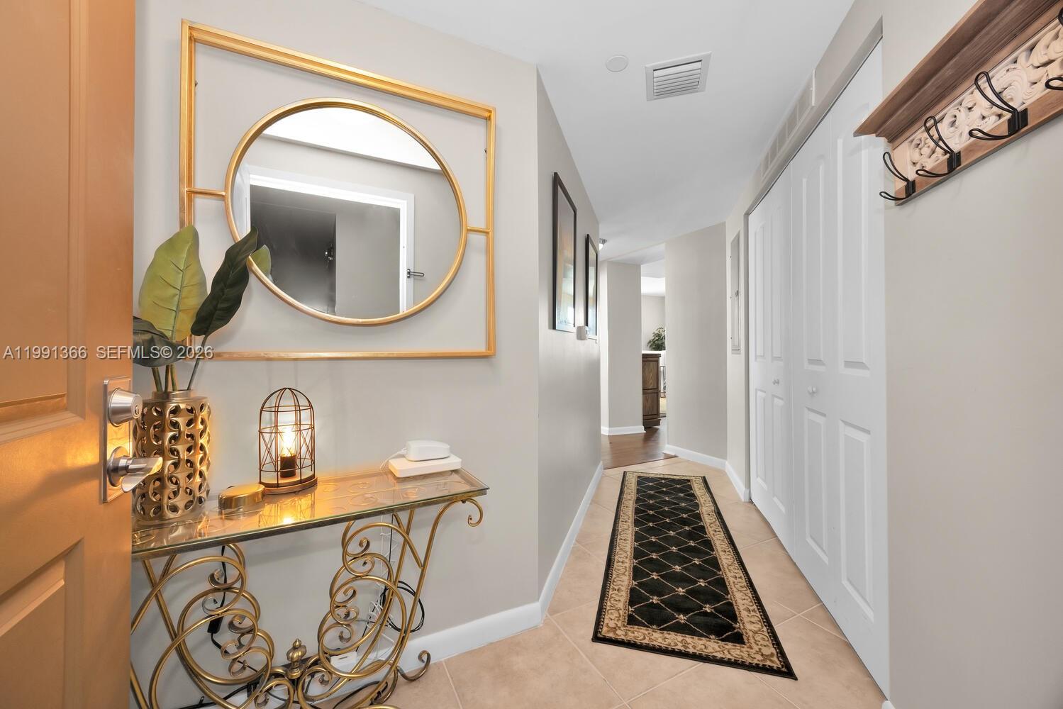 An entryway features a glass console table, a gold-framed mirror, and a black runner rug — 7350 SW 89th St # 1511S, Miami FL 33156, MIAMI, FL