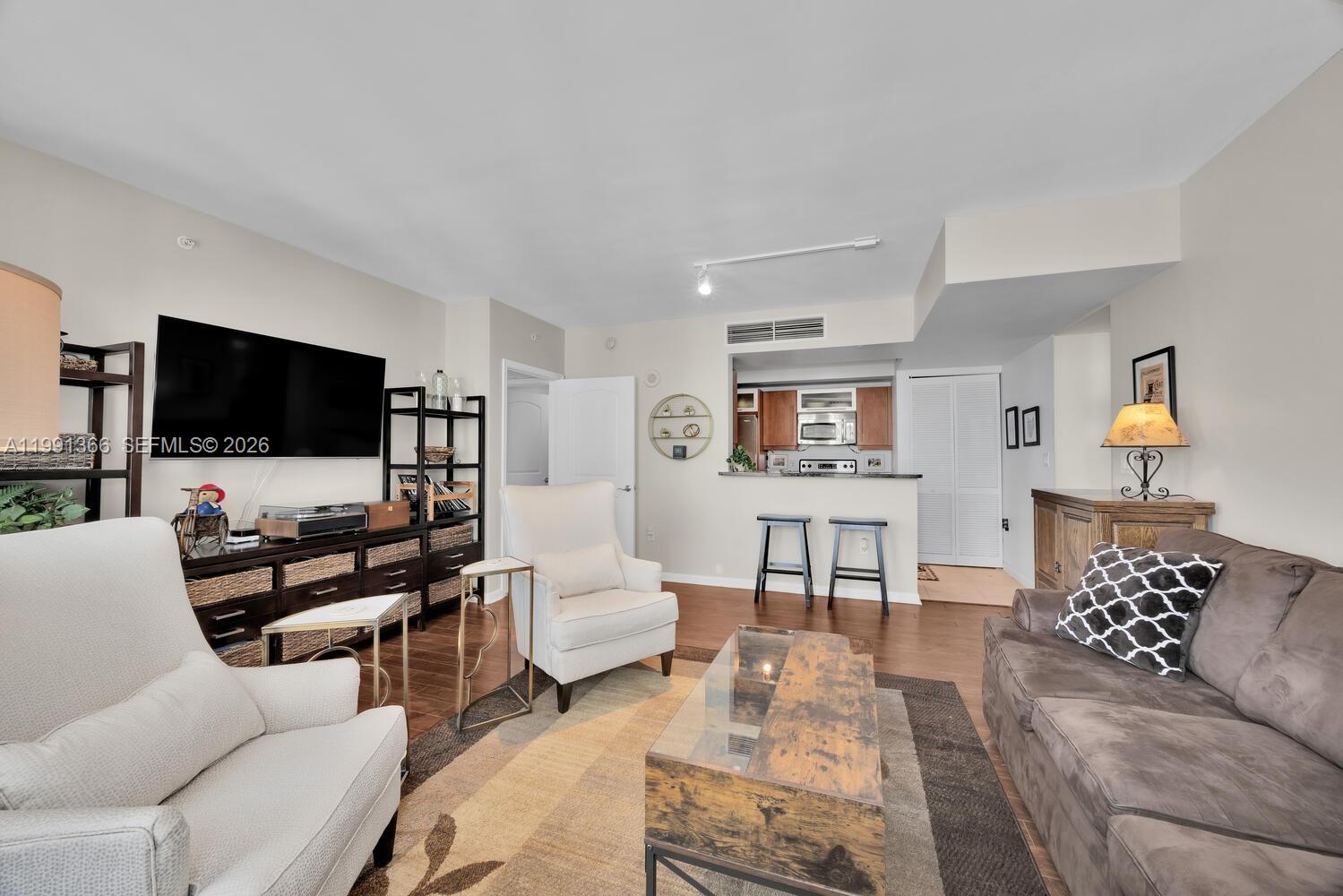 A living room features a brown sofa, two armchairs, a television, and an open kitchen — 7350 SW 89th St # 1511S, Miami FL 33156, MIAMI, FL