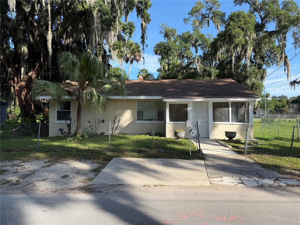 A single-story house with a palm tree, chain-link fence, and a dirt driveway — 921 WINCHESTER STREET, DAYTONA BEACH, FL