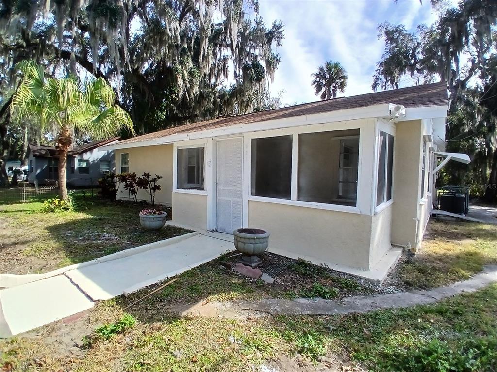 A single-story house with a screened porch, light-colored stucco walls, and a concrete walkway — 921 WINCHESTER STREET, DAYTONA BEACH, FL