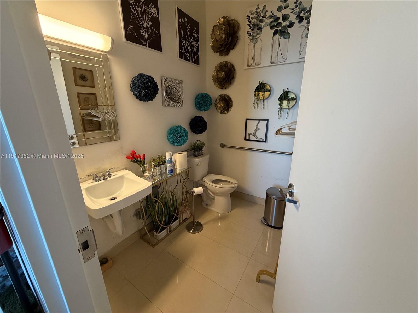 A bathroom features a wall-mounted sink, a toilet, and decorative wall art — 2201 Palm Ave, Miramar FL 33025, MIRAMAR, FL