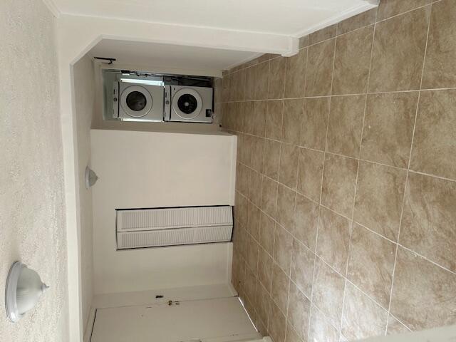 A room with tan tile flooring features a white door, a closet, and stacked laundry machines — 1400 Hernando Drive, Tallahassee FL 32304, TALLAHASSEE, FL