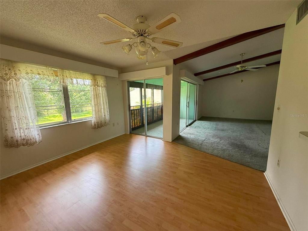 A living room features wood-look flooring, a ceiling fan, and a sliding door to a balcony — 2536 CLUBHOUSE CIRCLE UNIT 202, SARASOTA, FL