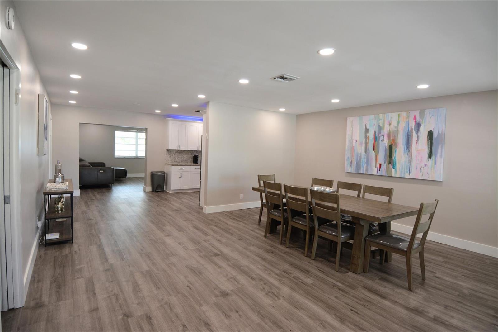 A dining room with a wooden table and chairs, wood-look flooring, and a large painting — 3840 N 42nd Terrace, Hollywood FL 33021, HOLLYWOOD, FL