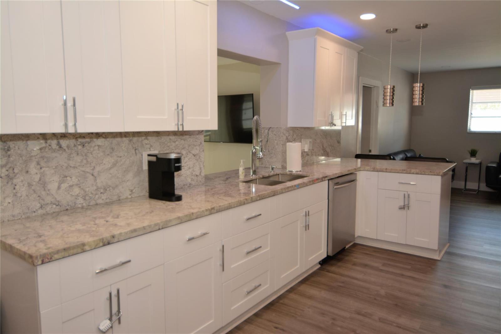 A modern kitchen features white shaker cabinets, granite countertops, stainless steel appliances, and pendant lighting — 3840 N 42nd Terrace, Hollywood FL 33021, HOLLYWOOD, FL