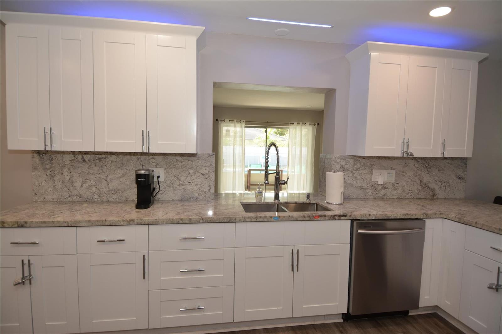 A kitchen features white shaker cabinets, granite countertops, a stainless steel dishwasher, and blue lighting — 3840 N 42nd Terrace, Hollywood FL 33021, HOLLYWOOD, FL