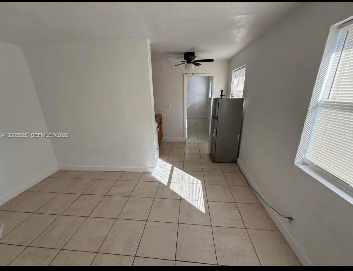 A room with light-colored tile flooring, white walls, a ceiling fan, and a refrigerator — 5731 Flagler St # 1, Hollywood FL 33023, HOLLYWOOD, FL