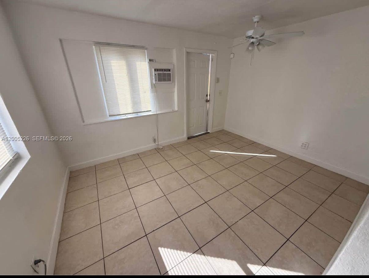 An empty room features beige tile flooring, a ceiling fan, and a window air conditioner — 5731 Flagler St # 1, Hollywood FL 33023, HOLLYWOOD, FL