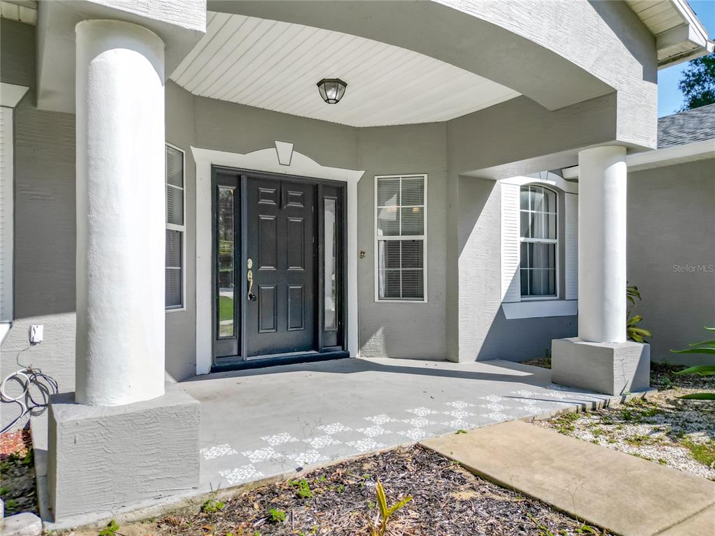 The exterior entryway features a covered porch with two white columns and a dark door — 12805 SW 64TH LANE, OCALA, FL