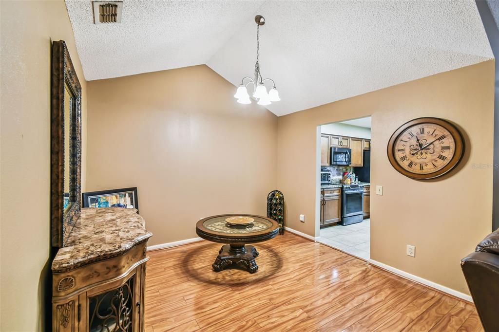 A dining area features wood flooring, a round table, a chandelier, and a wall clock — 2817 WINGFOOT COURT, WINTER HAVEN, FL