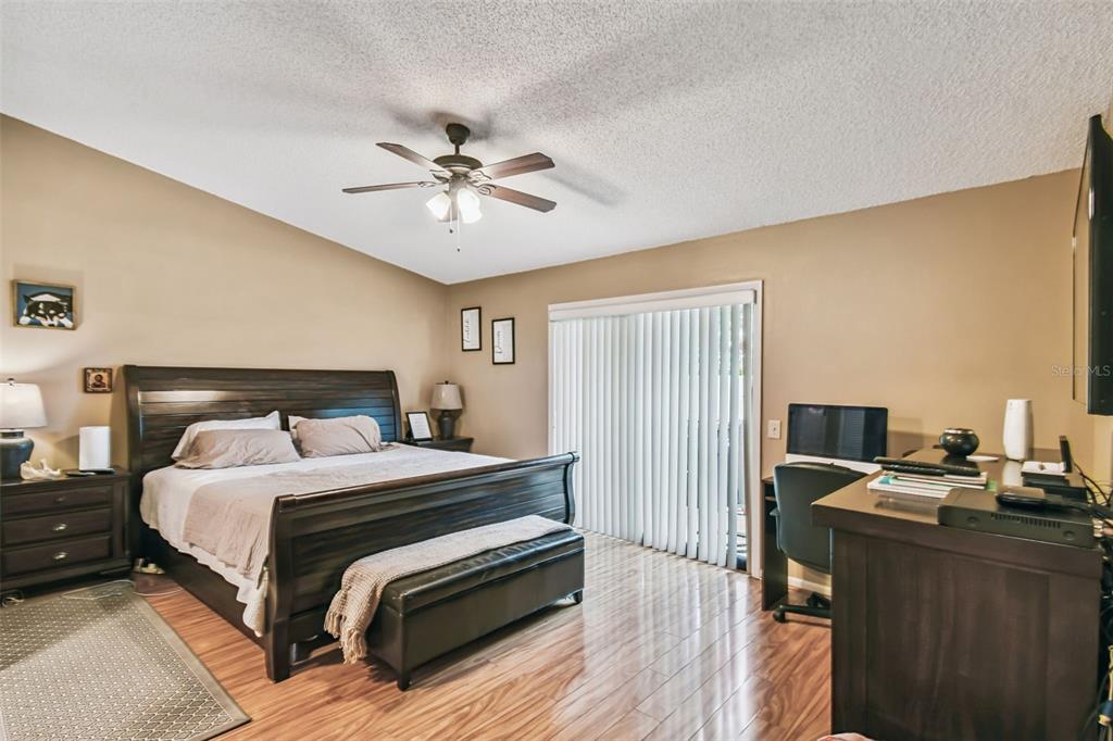 A bedroom features a dark wood sleigh bed, a ceiling fan, and wood-look flooring — 2817 WINGFOOT COURT, WINTER HAVEN, FL
