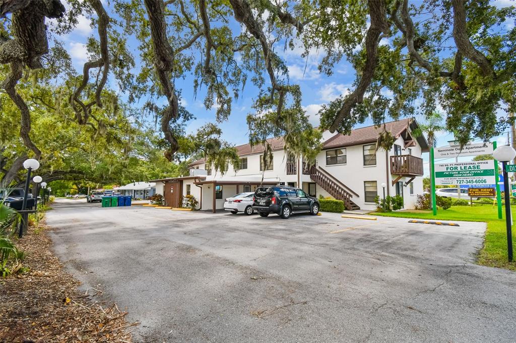 A two-story apartment building with a parking lot and large oak trees in front — 8423 SEMINOLE BLVD UNIT 203, SEMINOLE, FL