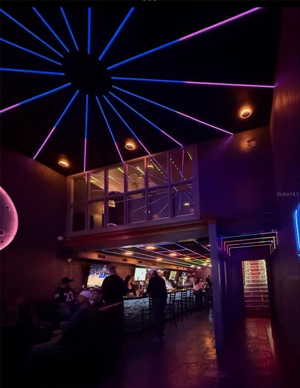 A dimly lit bar interior features neon ceiling lights, a lofted area, and a stone counter — DOWNTOWN BAR, ORLANDO, FL