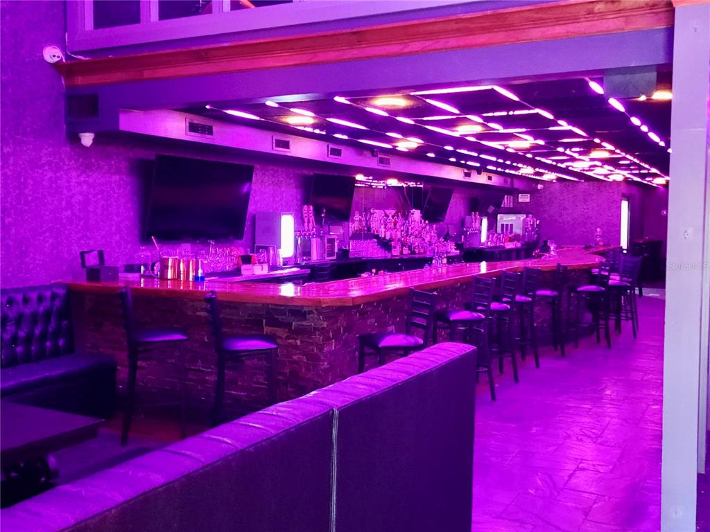 A bar area features a long counter, bar stools, and purple ambient lighting — DOWNTOWN BAR, ORLANDO, FL