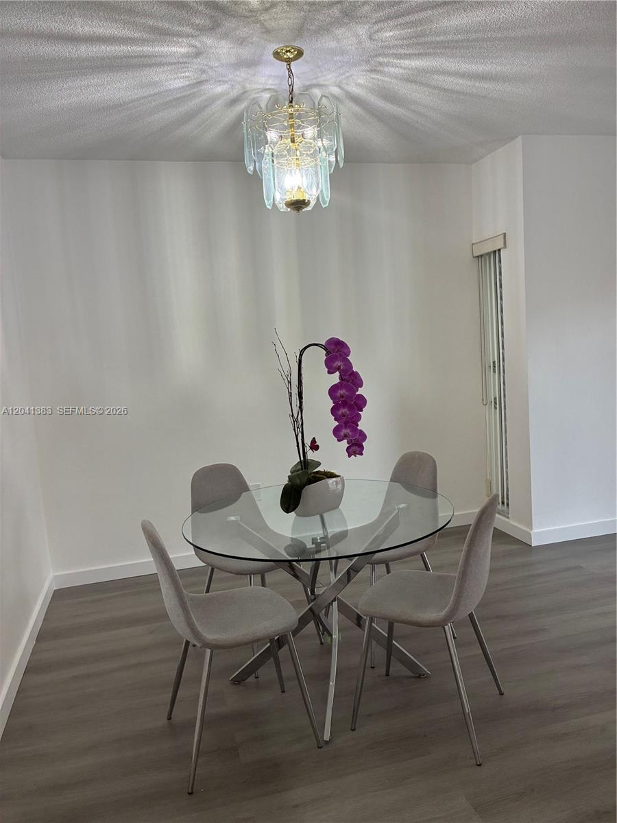 A dining area features a glass-topped table, four gray chairs, and a crystal chandelier — 9159 SW 77th Ave # 211, Miami FL 33156, MIAMI, FL